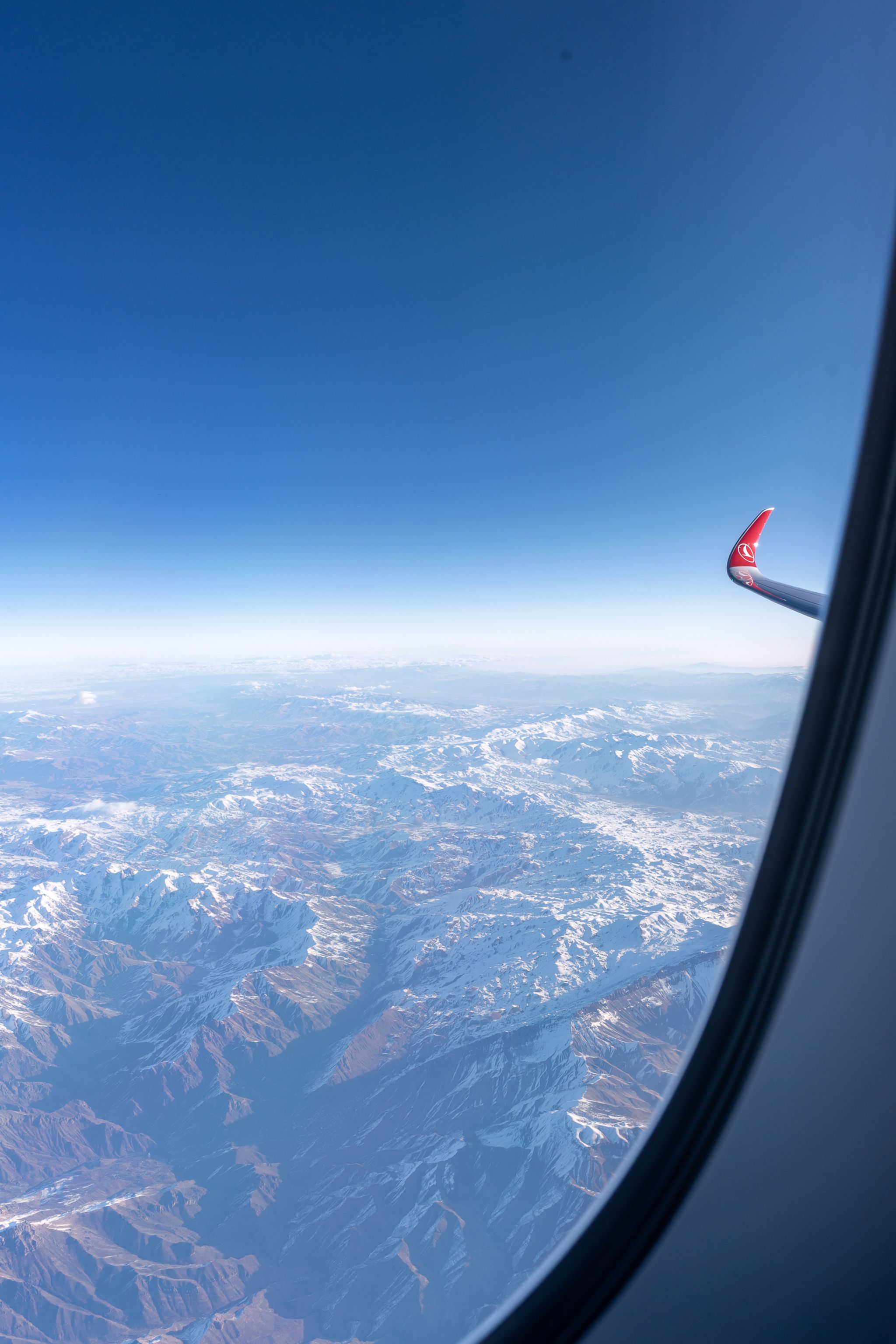 View of snow-capped mountains and a Turkish Airlines wingtip from the window