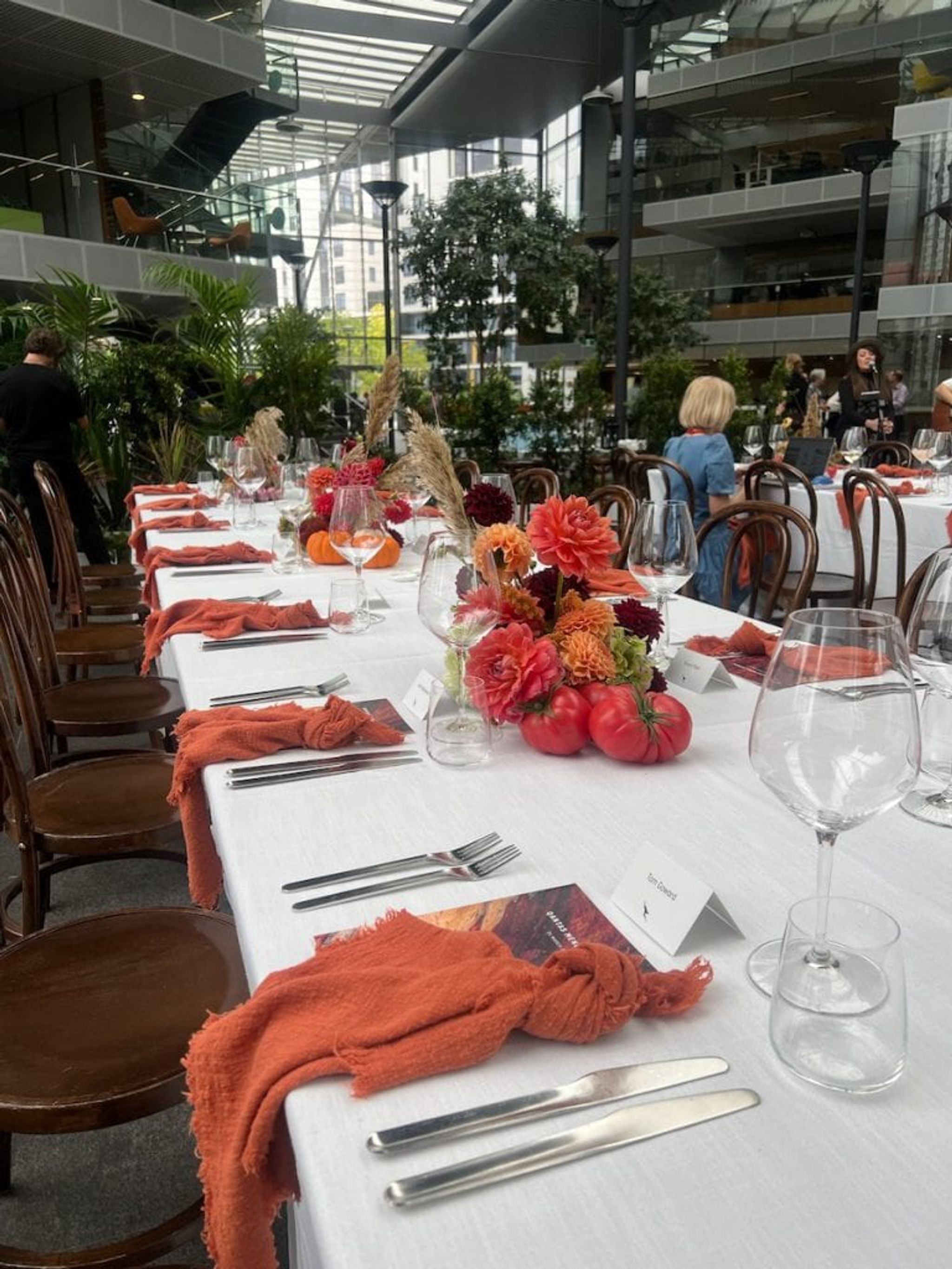 Long table set for the Qantas new menu launch with flowers and orange napkins