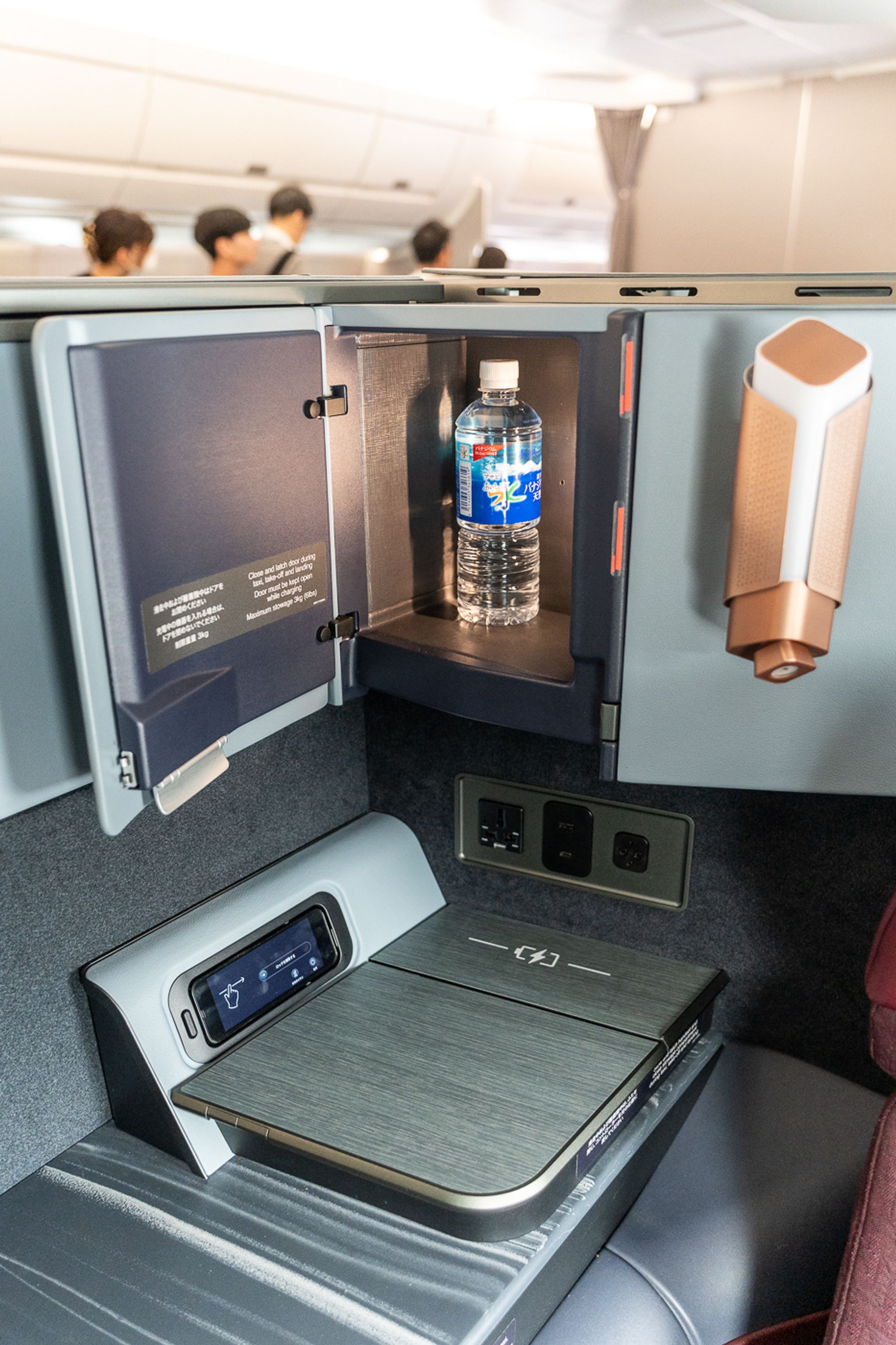 Side storage, water bottle and charging pad at a Japan Airlines A350-1000 business class seat