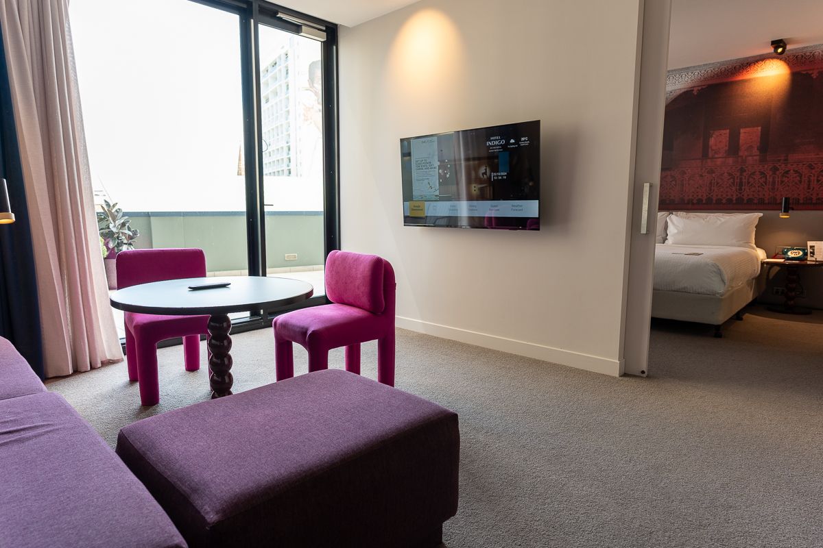 Hotel Indigo Sydney suite lounge with pink chairs, a round table and doors to the terrace