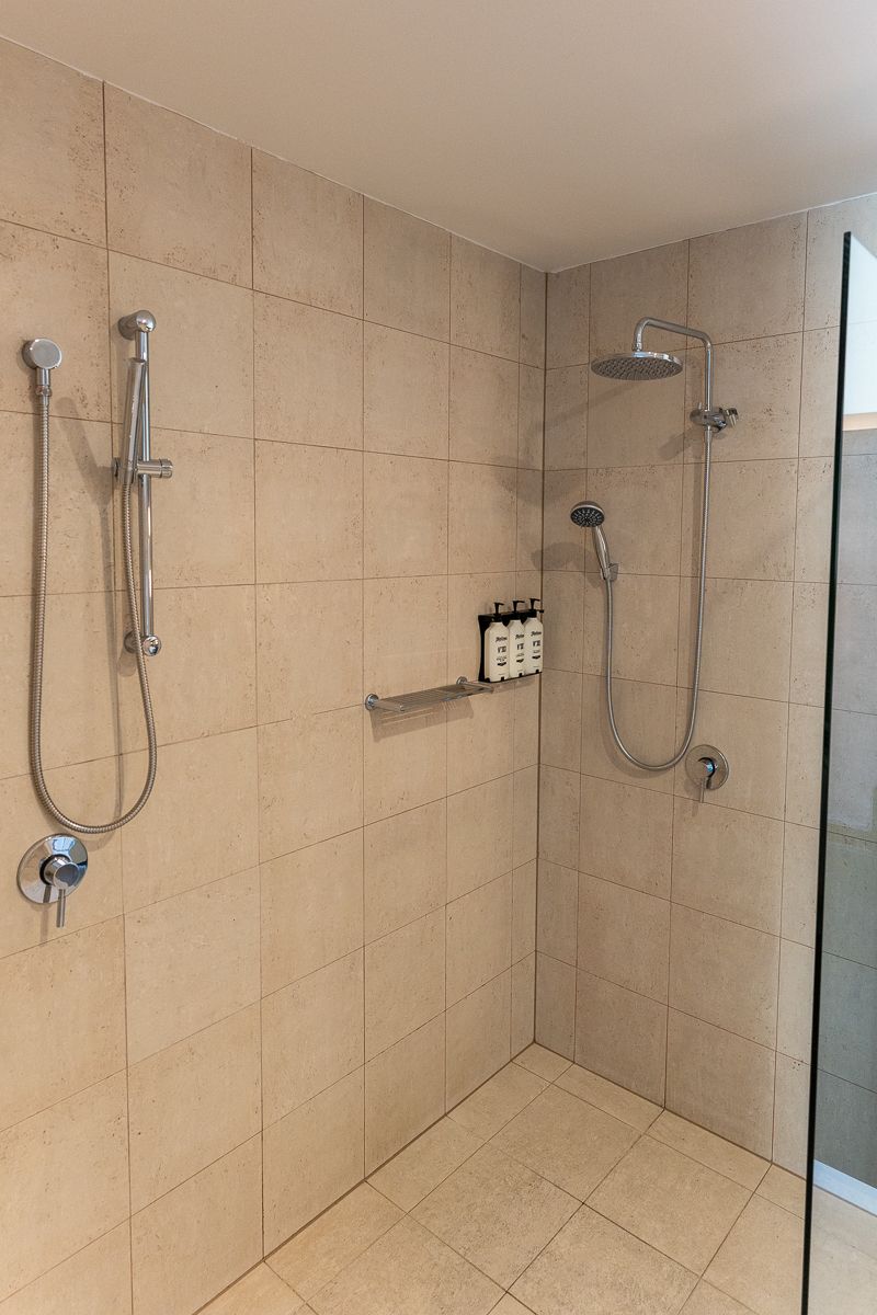 Tiled shower with rain and hand showerheads at Hotel Indigo Sydney Potts Point