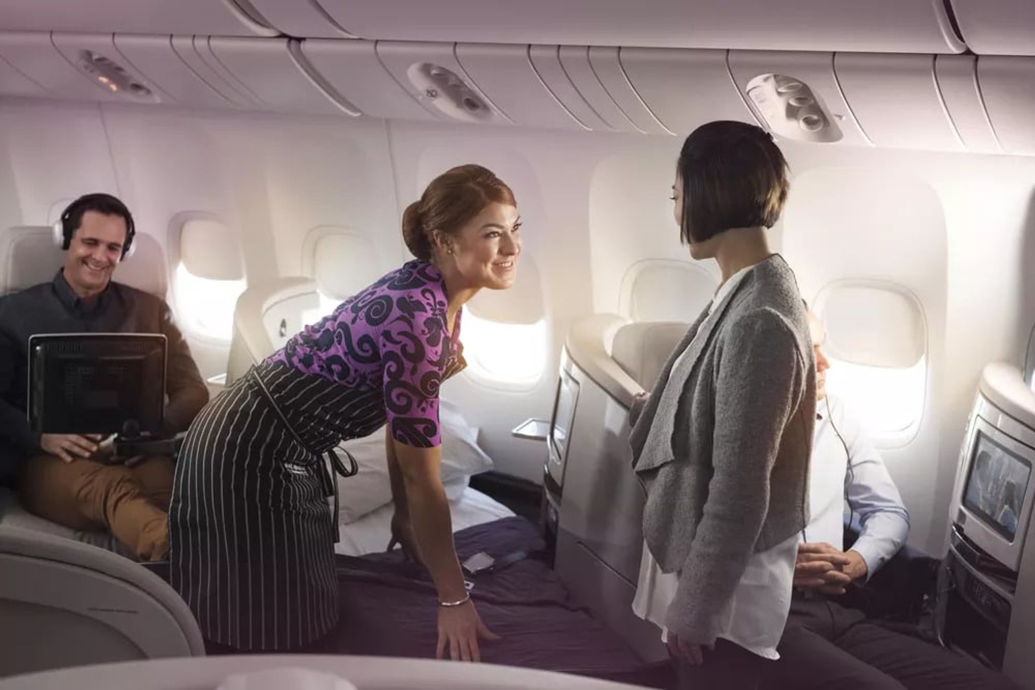 Flight attendant attending to passengers in Air New Zealand business class