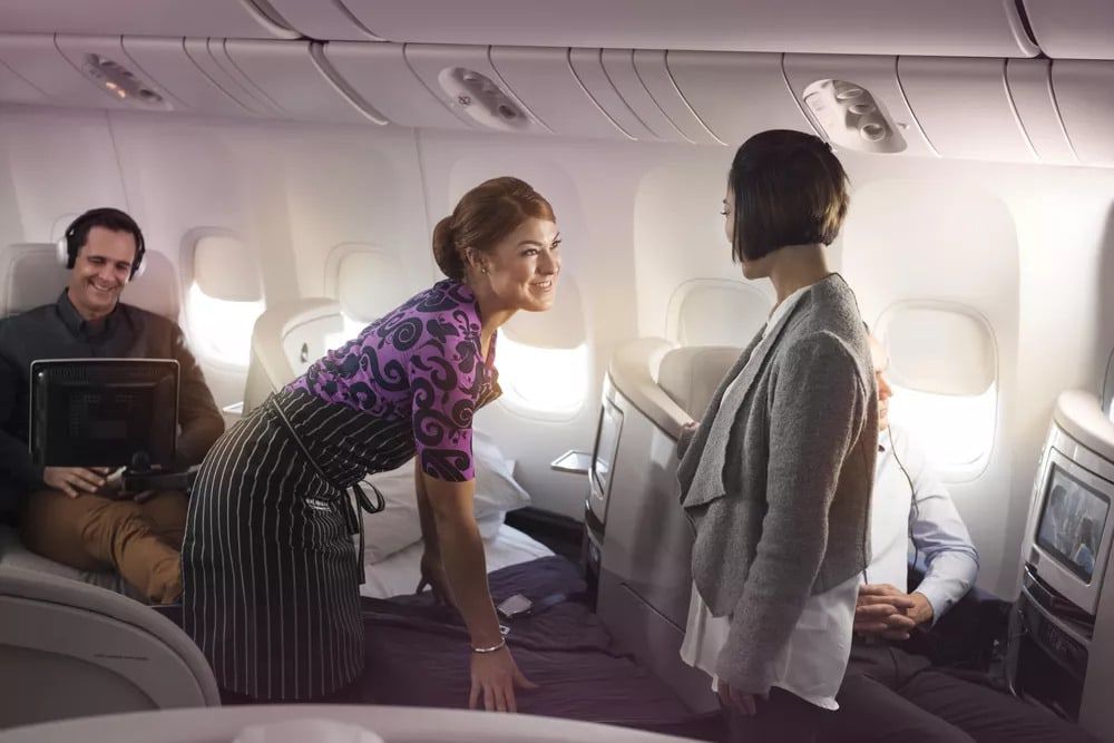 Flight attendant attending to passengers in Air New Zealand business class