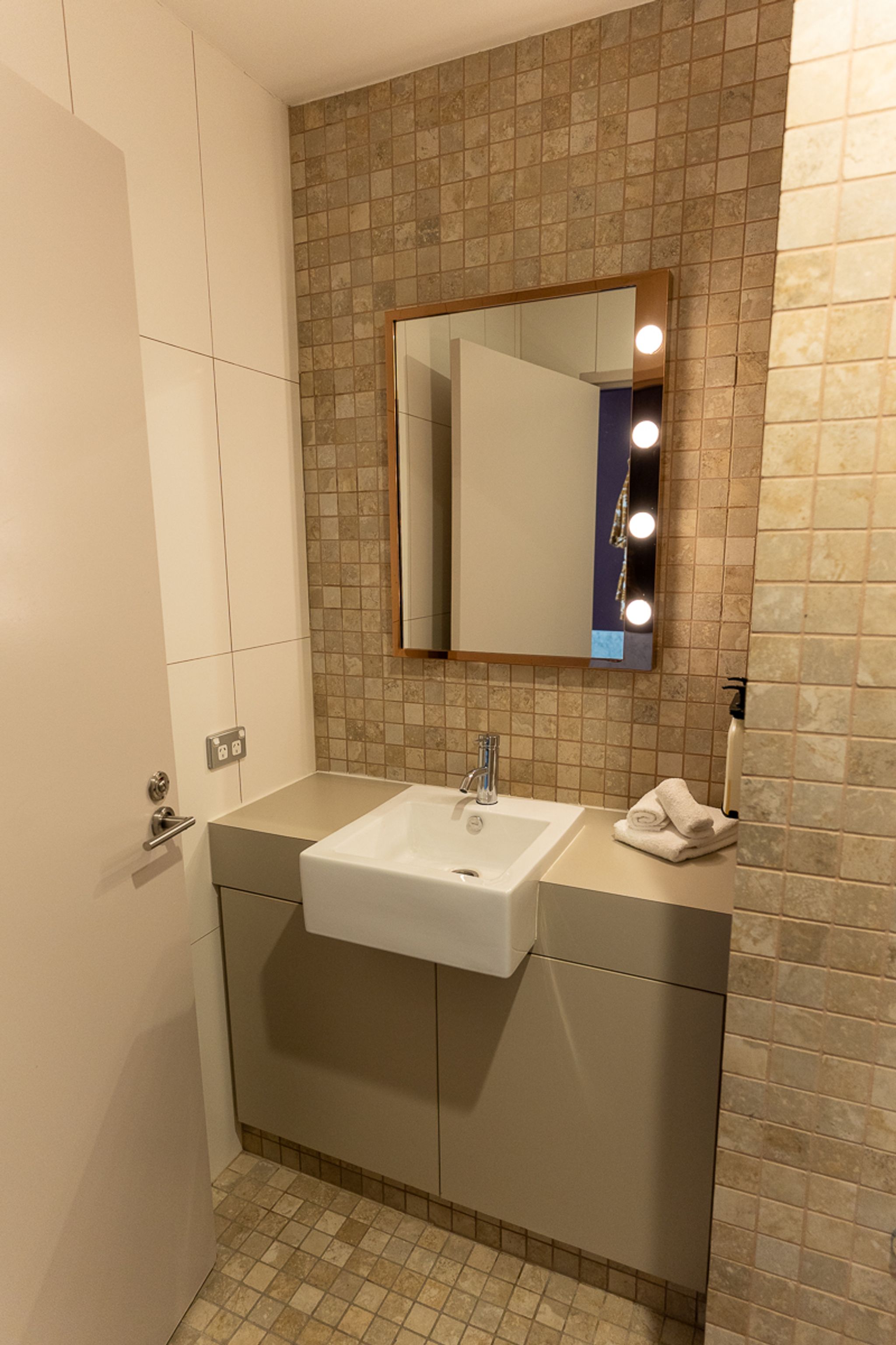 Guest bathroom with a vanity and lit mirror at Hotel Indigo Sydney
