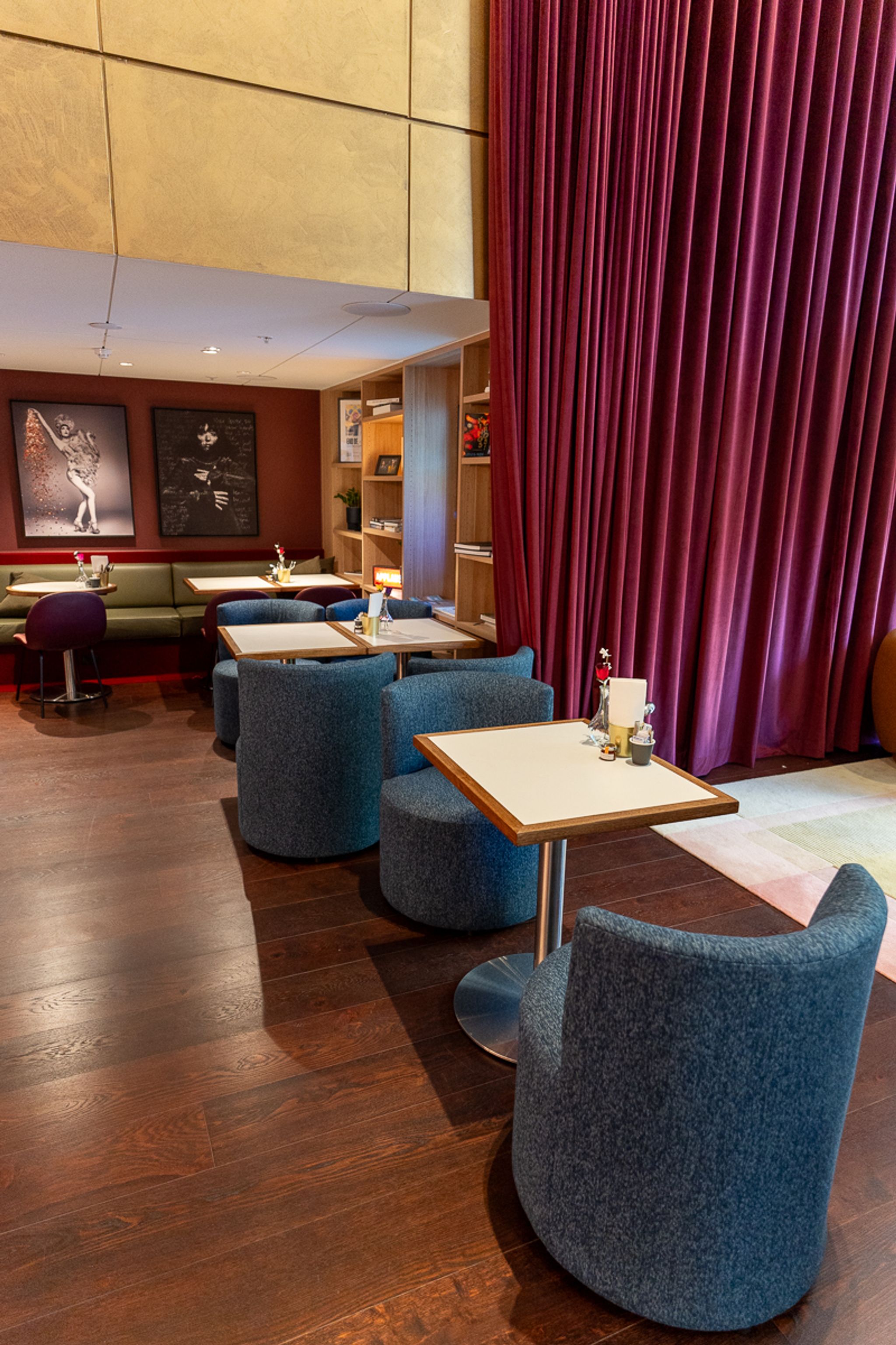 Hotel Indigo Sydney restaurant seating with blue armchairs and red velvet curtains