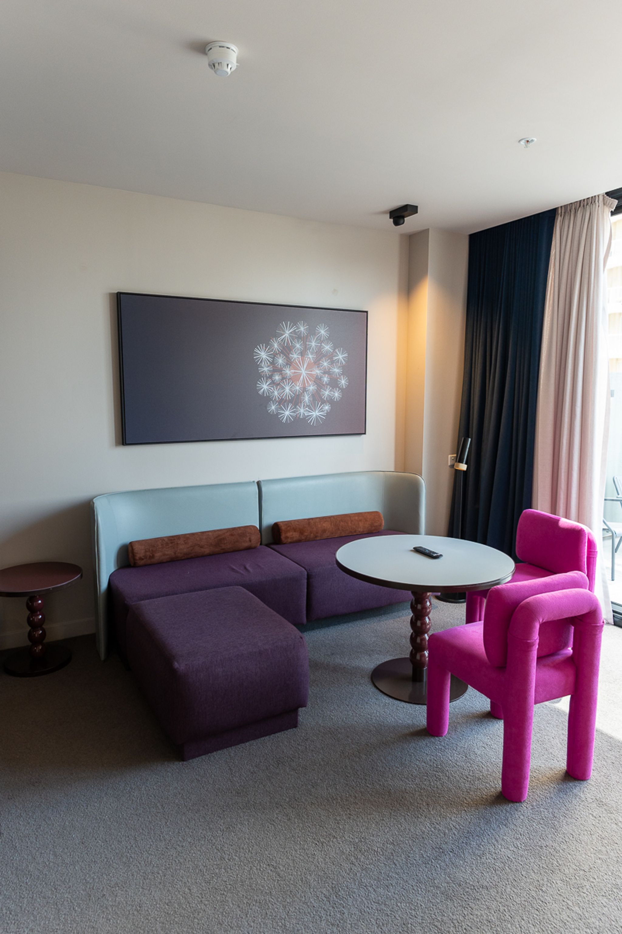Corner of the Hotel Indigo Sydney suite lounge with a purple sofa and pink chairs