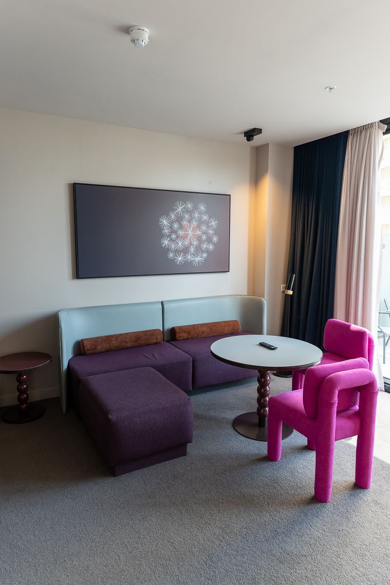 Corner of the Hotel Indigo Sydney suite lounge with a purple sofa and pink chairs