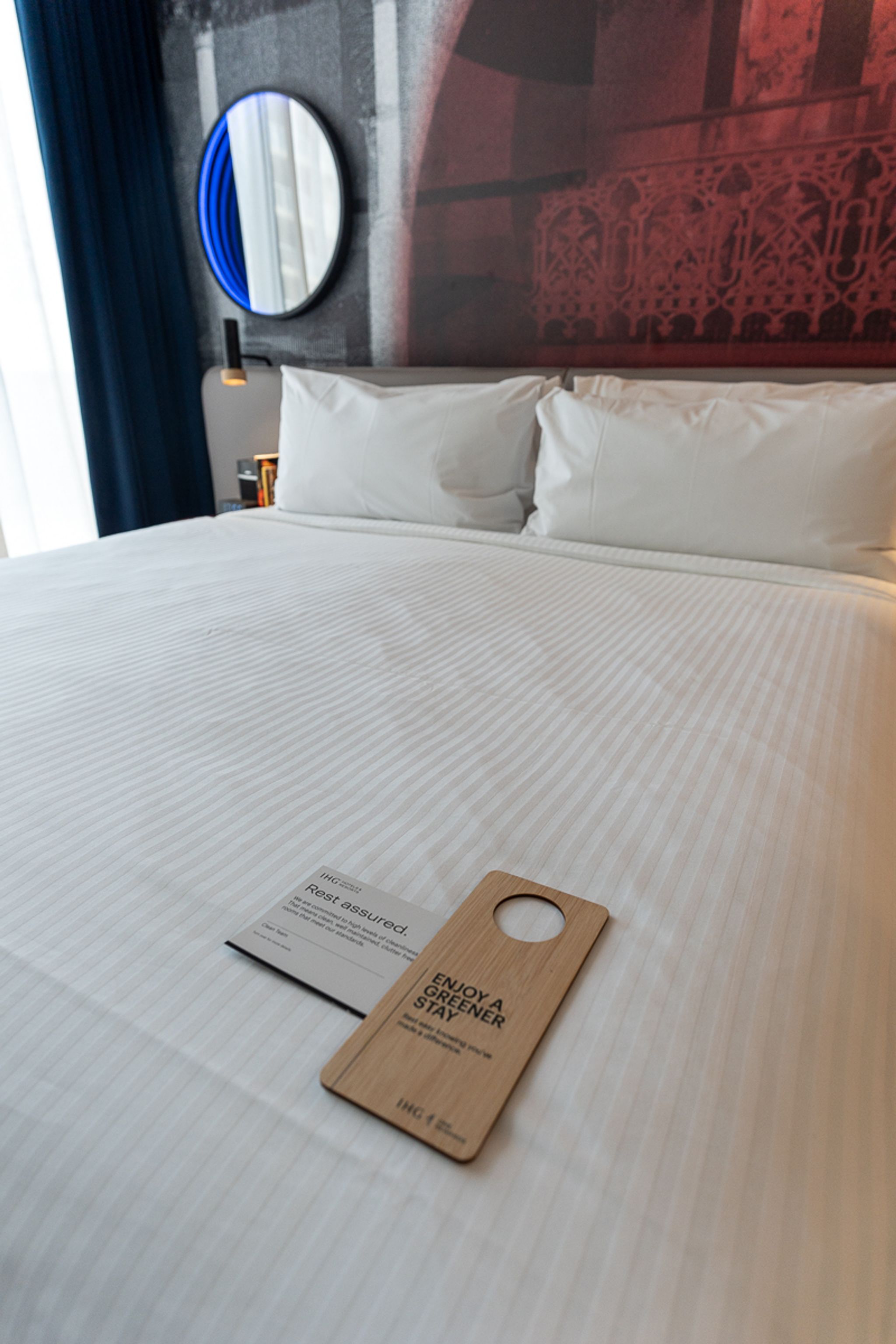 Bed made up with a green stay door hanger at Hotel Indigo Sydney