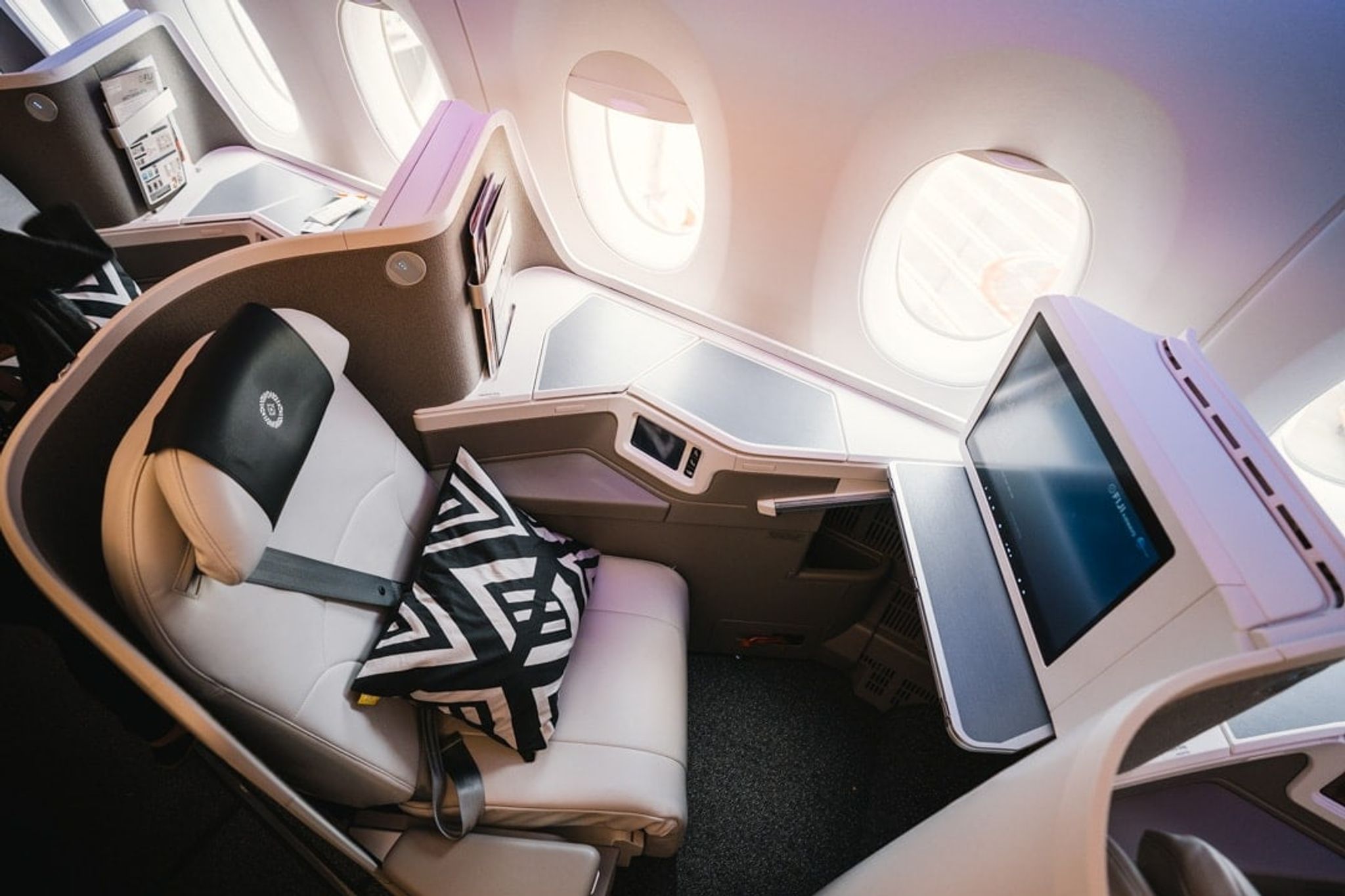 Qantas business class seat with a patterned cushion by the window