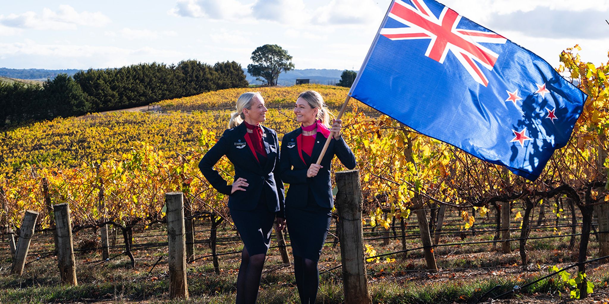 Qantas cabin crew holding a New Zealand flag in a vineyard