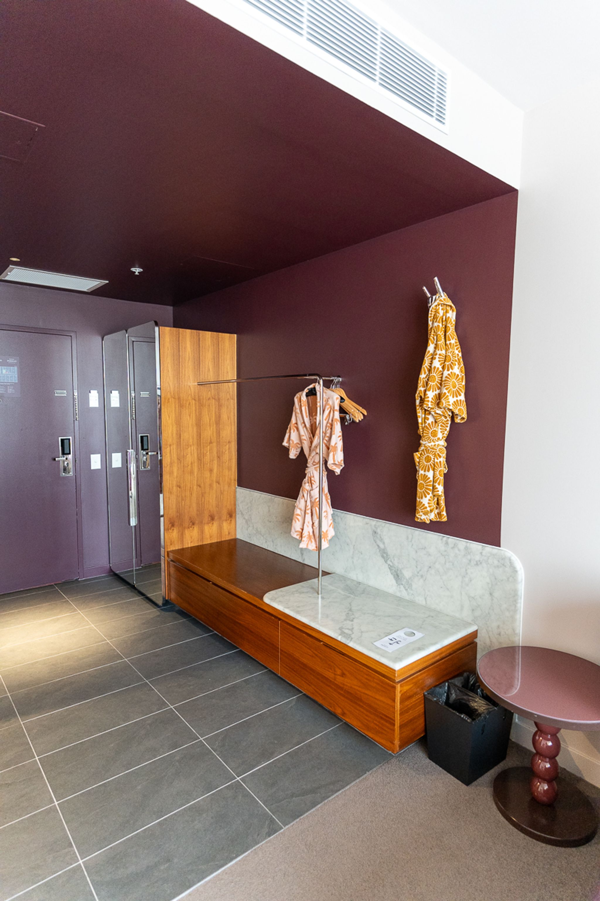 Hotel Indigo Sydney suite entry with bathrobes hanging beside a timber luggage bench