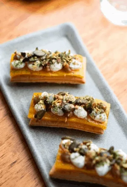 Savoury tarts topped with seeds served on a plate