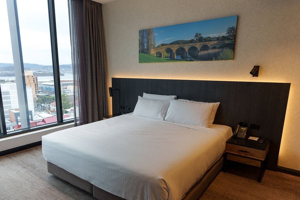King bed with harbour and city views in a Deluxe Harbour View room at Mövenpick Hobart