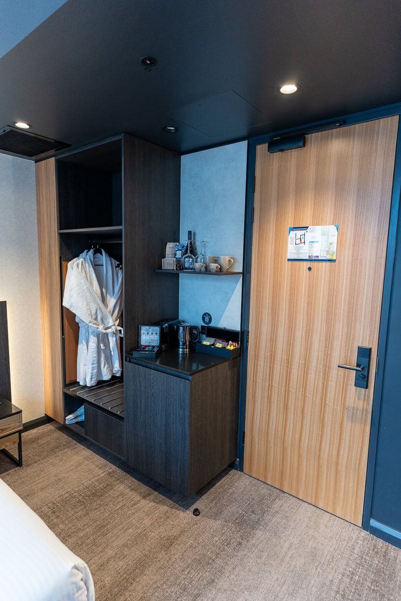 Entry of a Mövenpick Hobart room with wardrobe, bathrobes and coffee station